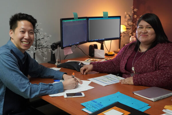 an image of a man sitting across the desk from a woman at a computer