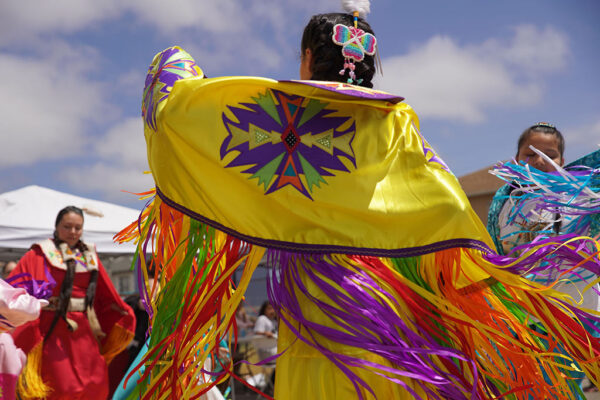 a person in a yellow robe dancing outside under a cloudy blue sky