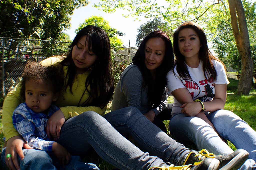 an image of a small child with his mother, aunt, and grandmother outside at a park